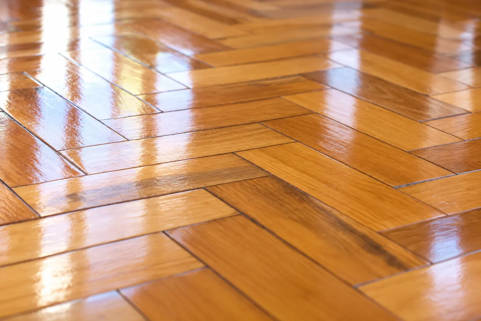 Parquet en espiga recién plastificado con el reflejo de la ventana