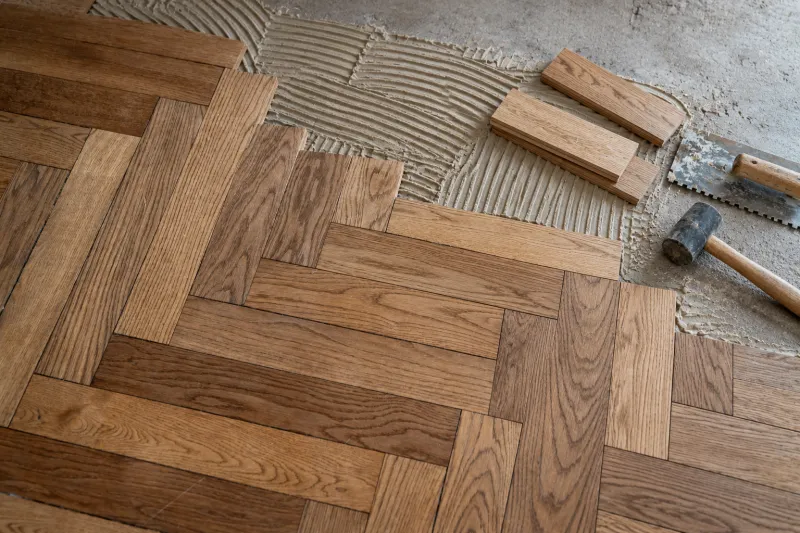 Colocación de parquet en espiga sobre la carpeta con adhesivo y llana dentada