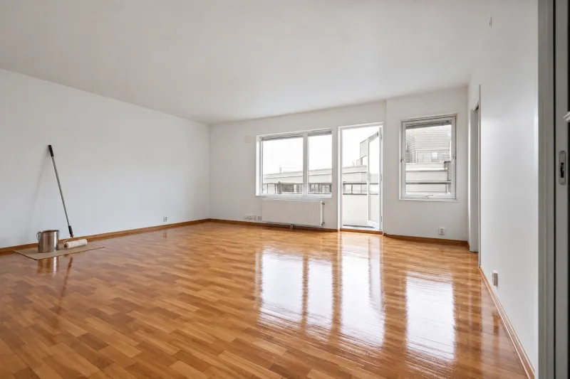 Parquet recién plastificado con brillo, con el rodillo y la lata de laca contra la pared